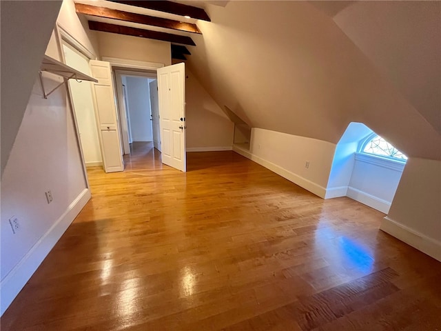 bonus room with lofted ceiling with beams and light wood-type flooring