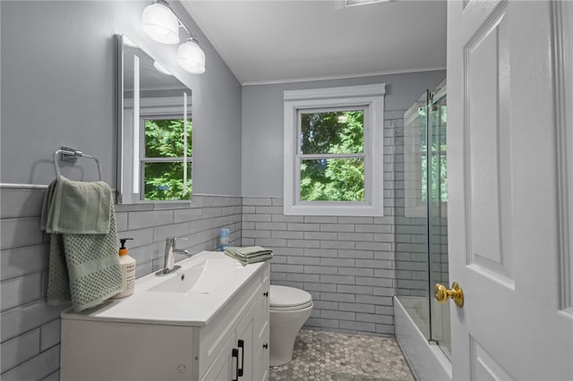 bathroom featuring tile patterned floors, toilet, tile walls, vanity, and crown molding