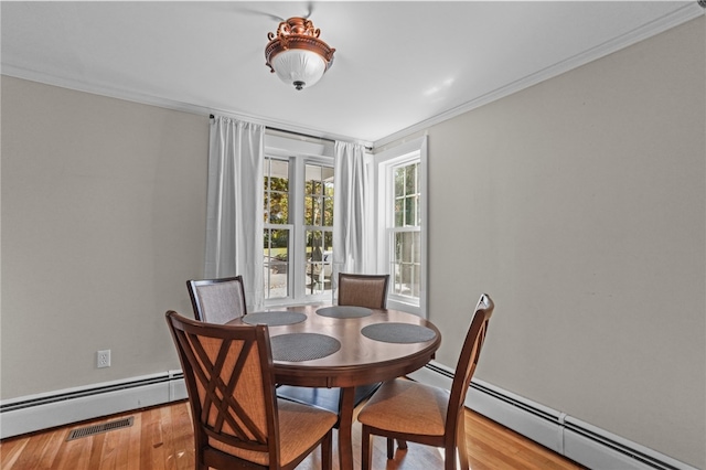 dining room featuring light wood-type flooring, baseboard heating, and ornamental molding