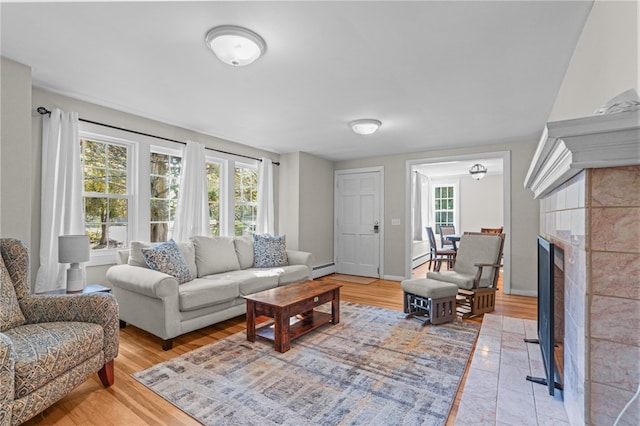 living room with a tiled fireplace, hardwood / wood-style flooring, and a baseboard heating unit