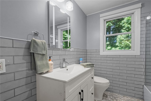 bathroom featuring toilet, vanity, ornamental molding, and tile walls