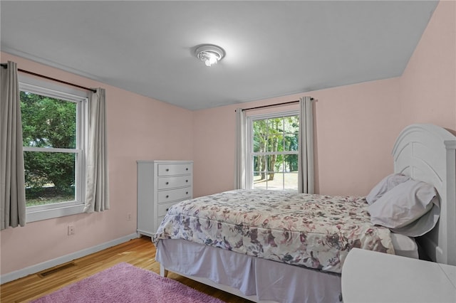 bedroom with light hardwood / wood-style floors and multiple windows