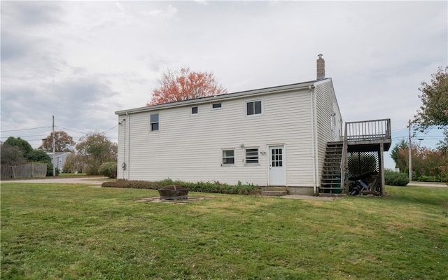 back of property featuring a wooden deck and a lawn