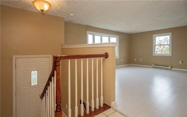 stairway with a baseboard radiator, a wealth of natural light, and a textured ceiling