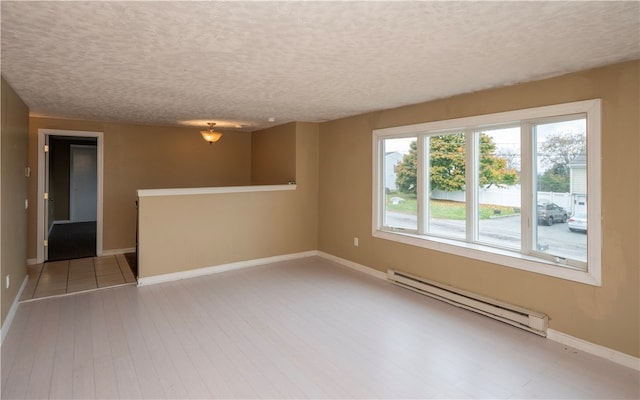 spare room featuring light hardwood / wood-style flooring, a textured ceiling, and a baseboard radiator