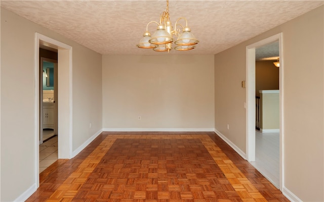 unfurnished room featuring parquet floors, a textured ceiling, and a chandelier