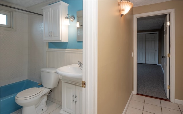 full bathroom featuring toilet, tiled shower / bath, sink, and tile patterned floors