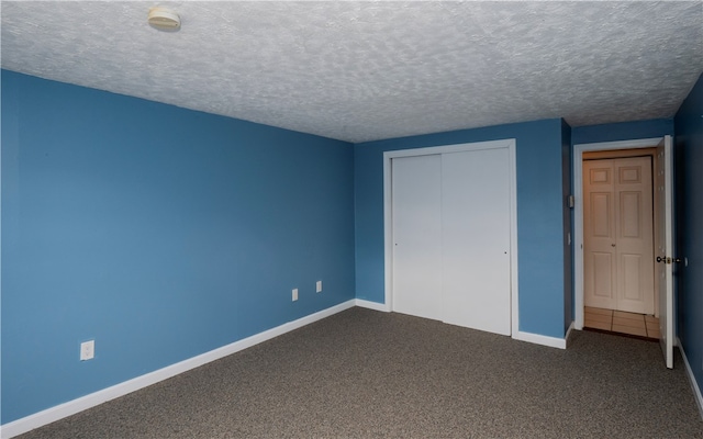 unfurnished bedroom with a closet, a textured ceiling, and dark carpet