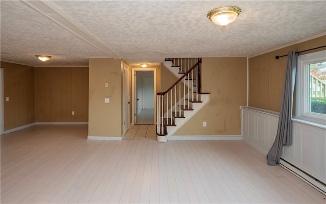 interior space featuring wooden walls, a textured ceiling, light hardwood / wood-style floors, and a baseboard radiator