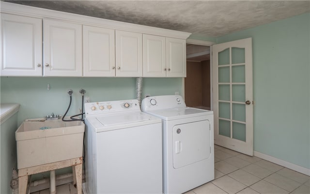 laundry room with cabinets, a textured ceiling, light tile patterned floors, sink, and washer and dryer