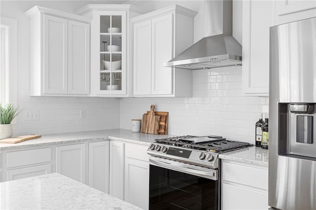 kitchen featuring white cabinetry, decorative backsplash, wall chimney exhaust hood, and stainless steel appliances