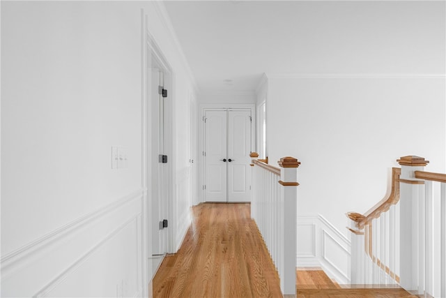 corridor featuring light wood-type flooring and ornamental molding