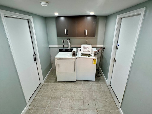 laundry area featuring washing machine and clothes dryer, light tile patterned floors, and cabinets