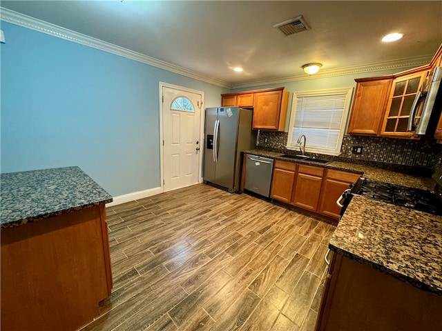 kitchen featuring sink, hardwood / wood-style flooring, ornamental molding, tasteful backsplash, and stainless steel appliances