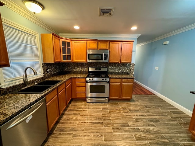 kitchen featuring dark stone counters, sink, hardwood / wood-style floors, and appliances with stainless steel finishes