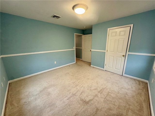 unfurnished bedroom featuring light colored carpet and a closet