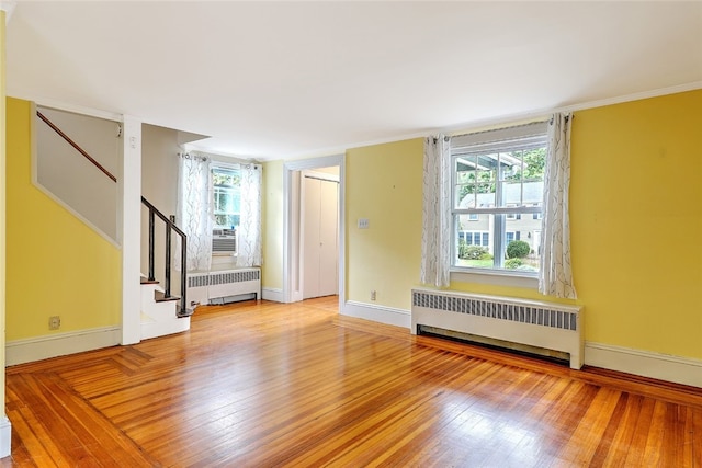 empty room featuring plenty of natural light, radiator heating unit, and light hardwood / wood-style flooring