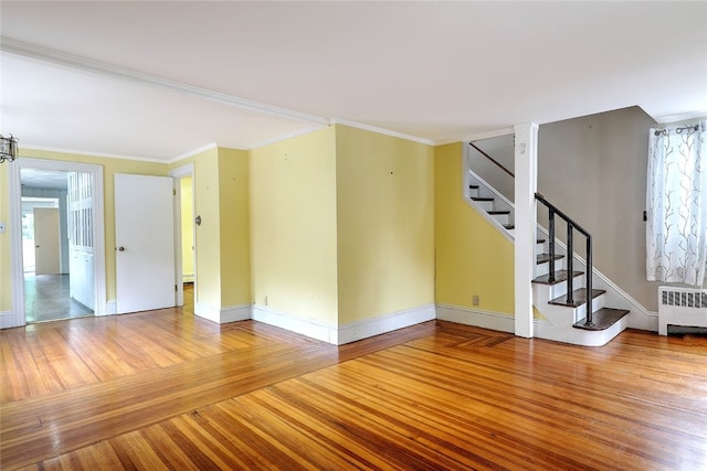 unfurnished living room with hardwood / wood-style floors, radiator heating unit, and ornamental molding