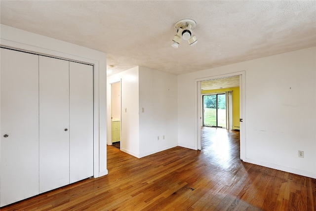 unfurnished bedroom with hardwood / wood-style flooring, a textured ceiling, and a closet