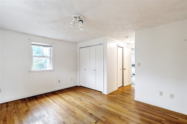 unfurnished bedroom featuring a textured ceiling and light hardwood / wood-style flooring