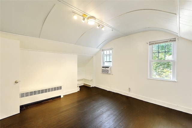 additional living space with dark wood-type flooring, radiator heating unit, vaulted ceiling, and cooling unit