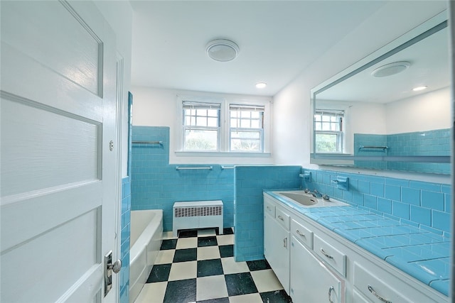 bathroom with vanity, radiator heating unit, tile walls, and a bathing tub