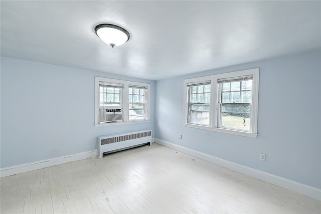 empty room with light hardwood / wood-style floors and radiator heating unit