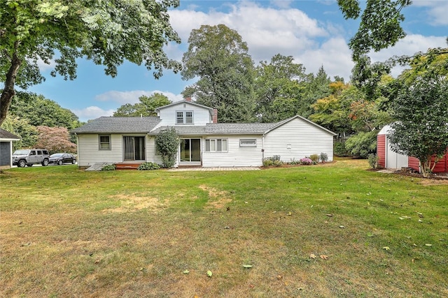 back of house with a storage unit and a yard