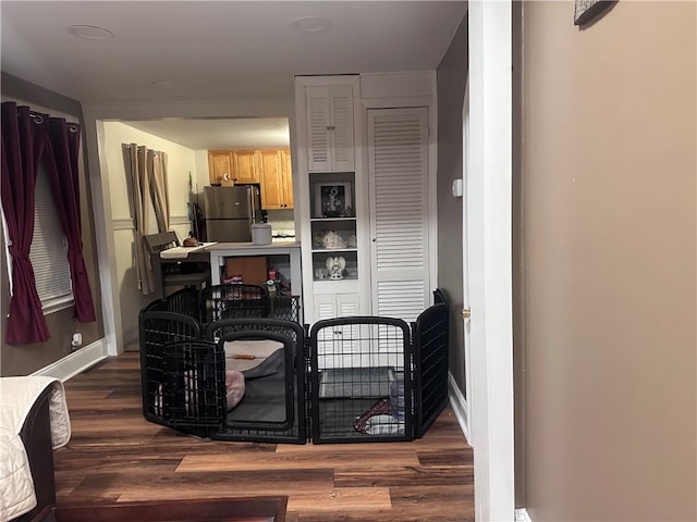 kitchen with dark wood-type flooring, light brown cabinetry, and stainless steel fridge