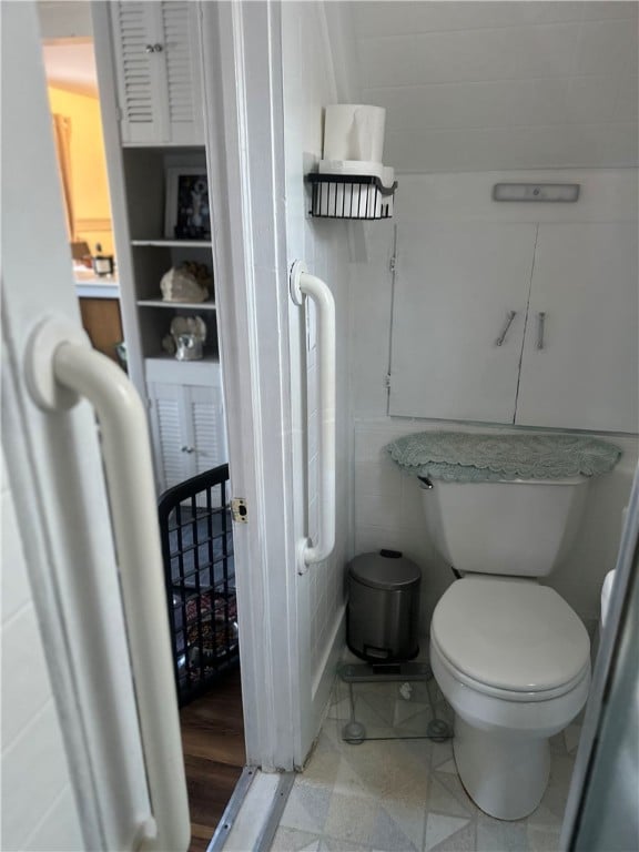 bathroom with tile walls and toilet