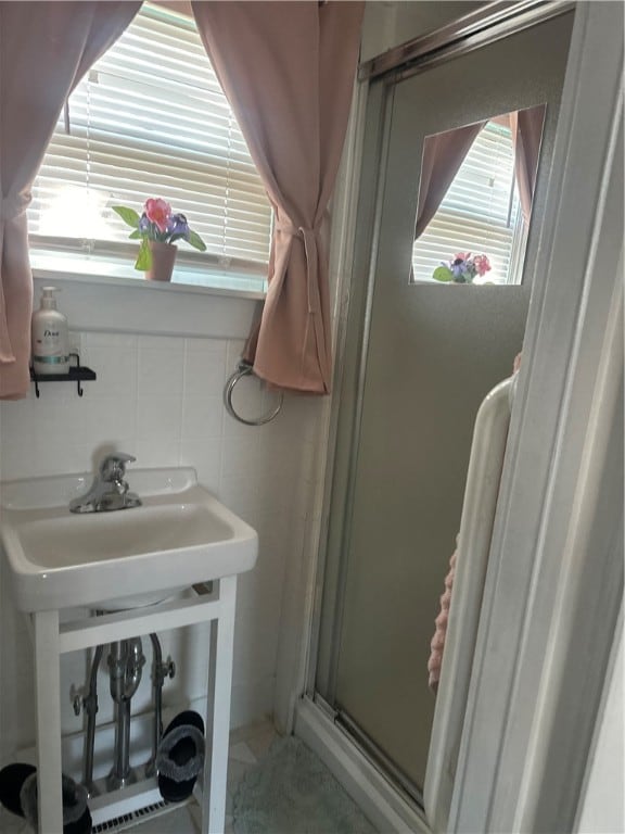 bathroom with walk in shower, backsplash, and tile walls