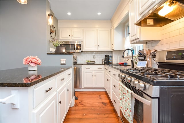 kitchen featuring light hardwood / wood-style floors, white cabinets, sink, extractor fan, and appliances with stainless steel finishes