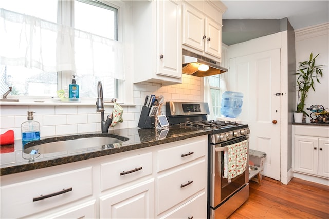 kitchen featuring light hardwood / wood-style floors, white cabinetry, sink, dark stone countertops, and stainless steel gas range oven