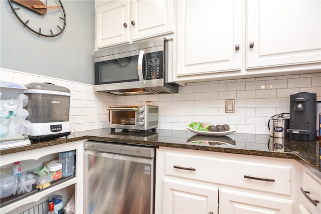 kitchen with dark stone countertops, white cabinetry, appliances with stainless steel finishes, and backsplash