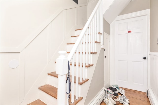 stairway featuring baseboard heating and wood-type flooring