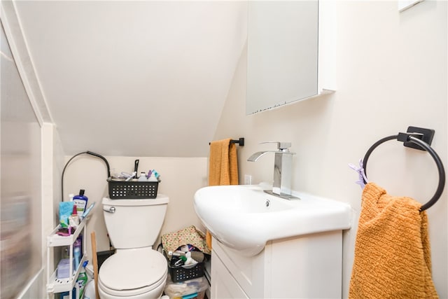 bathroom featuring toilet, vanity, and lofted ceiling