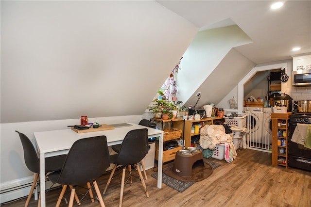 dining area with baseboard heating, hardwood / wood-style floors, lofted ceiling, and washing machine and clothes dryer