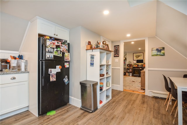 kitchen featuring white cabinetry, a baseboard heating unit, black fridge, and light hardwood / wood-style flooring