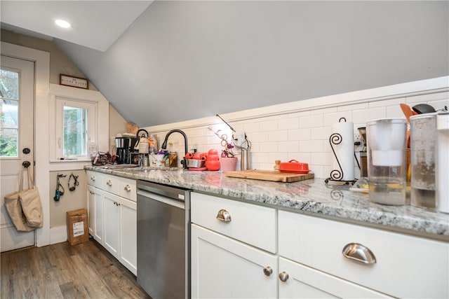 kitchen featuring wood-type flooring, light stone countertops, vaulted ceiling, white cabinets, and stainless steel dishwasher