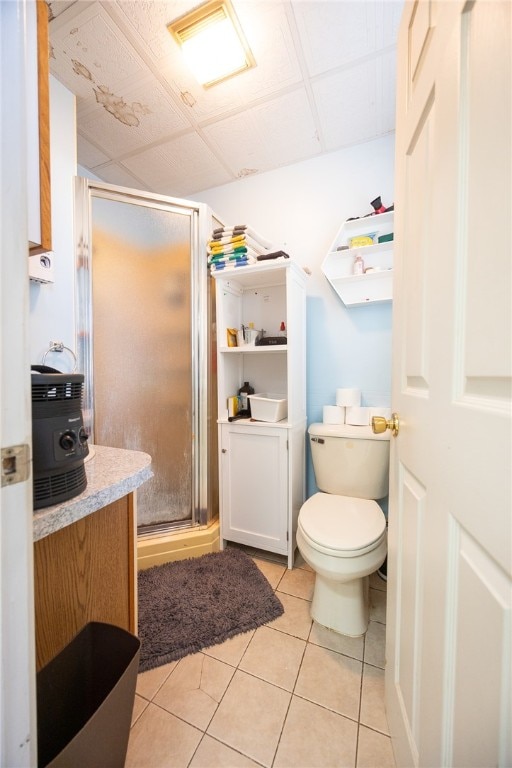 bathroom featuring toilet, tile patterned flooring, and a shower with shower door