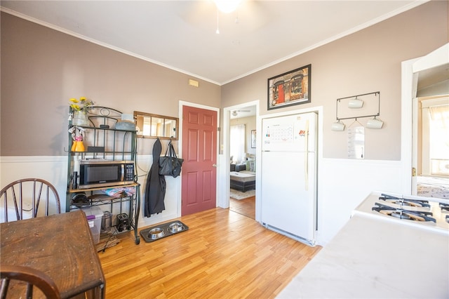 kitchen featuring white appliances, ceiling fan, crown molding, and light hardwood / wood-style floors