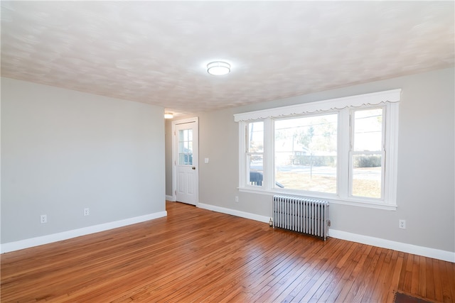 unfurnished room featuring radiator heating unit and light hardwood / wood-style flooring