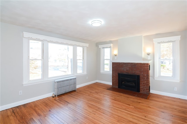 unfurnished living room featuring radiator, light wood-type flooring, and a fireplace