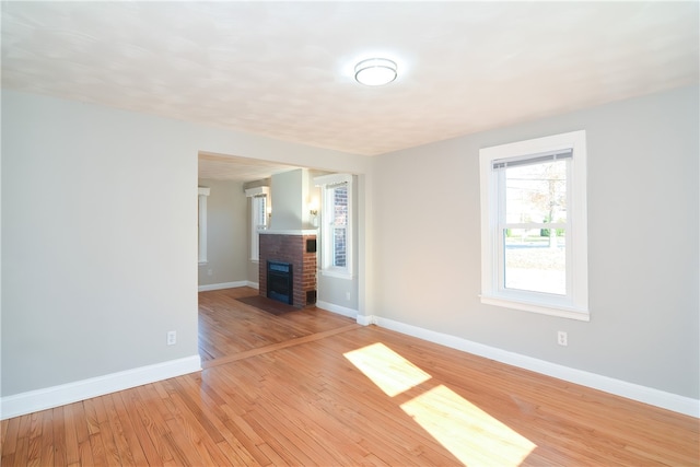 spare room featuring light hardwood / wood-style floors and a brick fireplace