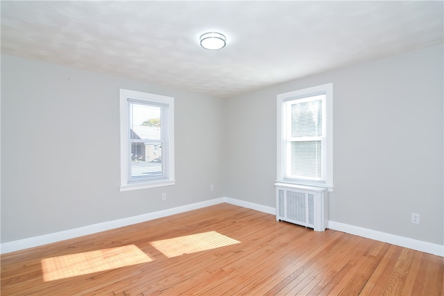 spare room with radiator heating unit and light hardwood / wood-style flooring