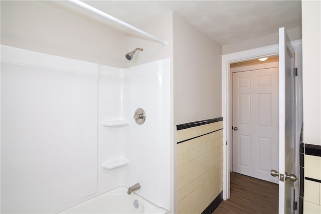 bathroom with tile walls, hardwood / wood-style flooring, and tub / shower combination