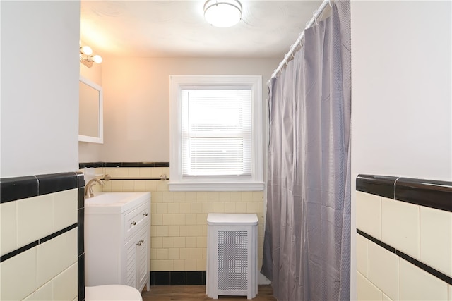 bathroom with tile walls, vanity, radiator, and wood-type flooring