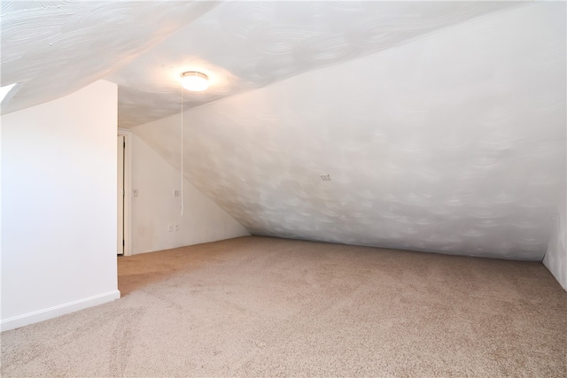 bonus room with light carpet and vaulted ceiling