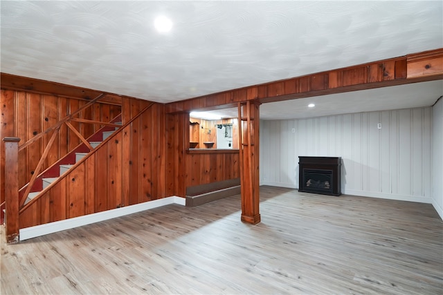 basement with wooden walls and light hardwood / wood-style flooring