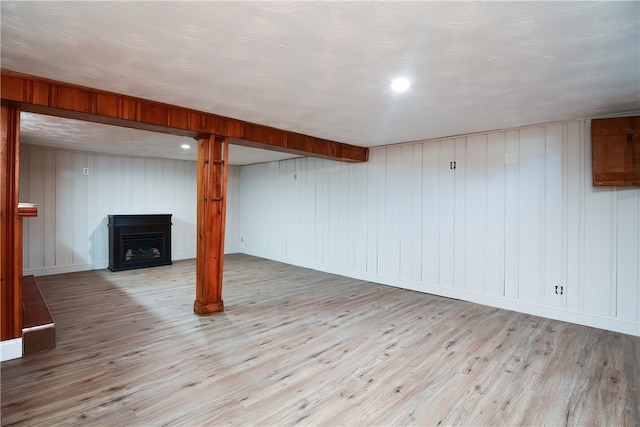 basement with light wood-type flooring and wooden walls